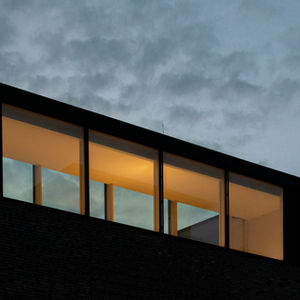 Minimal contemporary façade with a continuous band of dark-framed aluminium windows.
