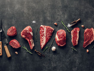 Animal-based diet foods including beef, eggs, fruit, and raw milk on slate