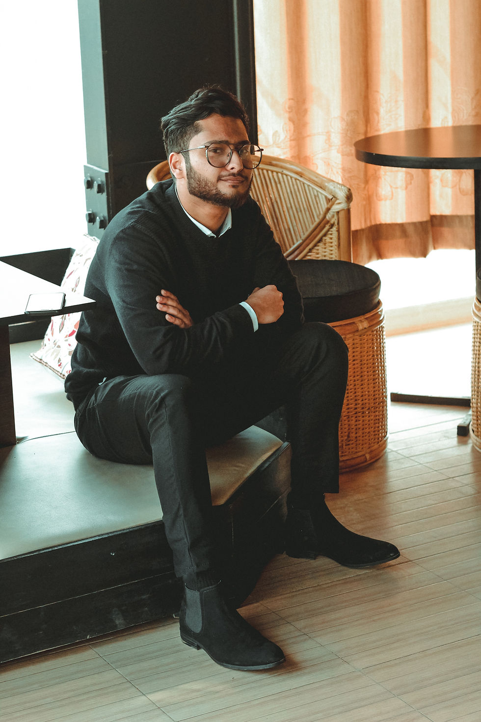 A man sitting in a booth with his arms crossed looking confident.