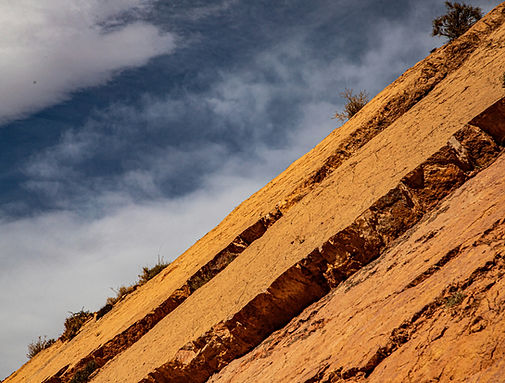 Tilted sedimentary rock layers beneath a dramatic sky. Photo by Bernd Dittrich.