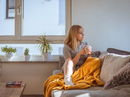 woman sitting on couch looking off to the side, thinking.