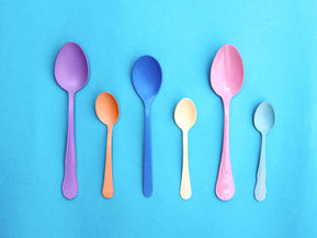Smorgasbord of colorful spoons arranged on a bright blue background representing how to be more mindful courtesy of The Spoon Theory.