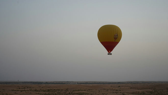 hot air balloon over desert dunes at sunrise, cinematic luxury travel, Middle East landscape