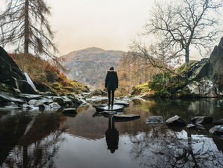 Woman standing on a rock on the lake with mountain back drop