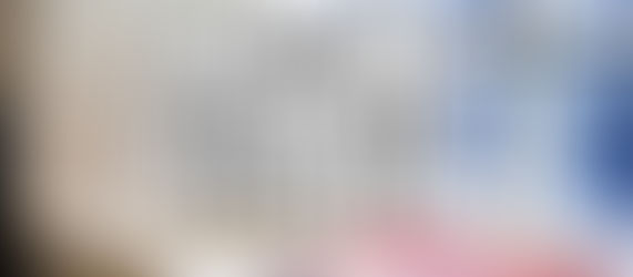 Lightbox sign with "TURN IDEAS INTO REALITY" in black text, next to colorful magazines on a wooden surface, set against a frosted window.