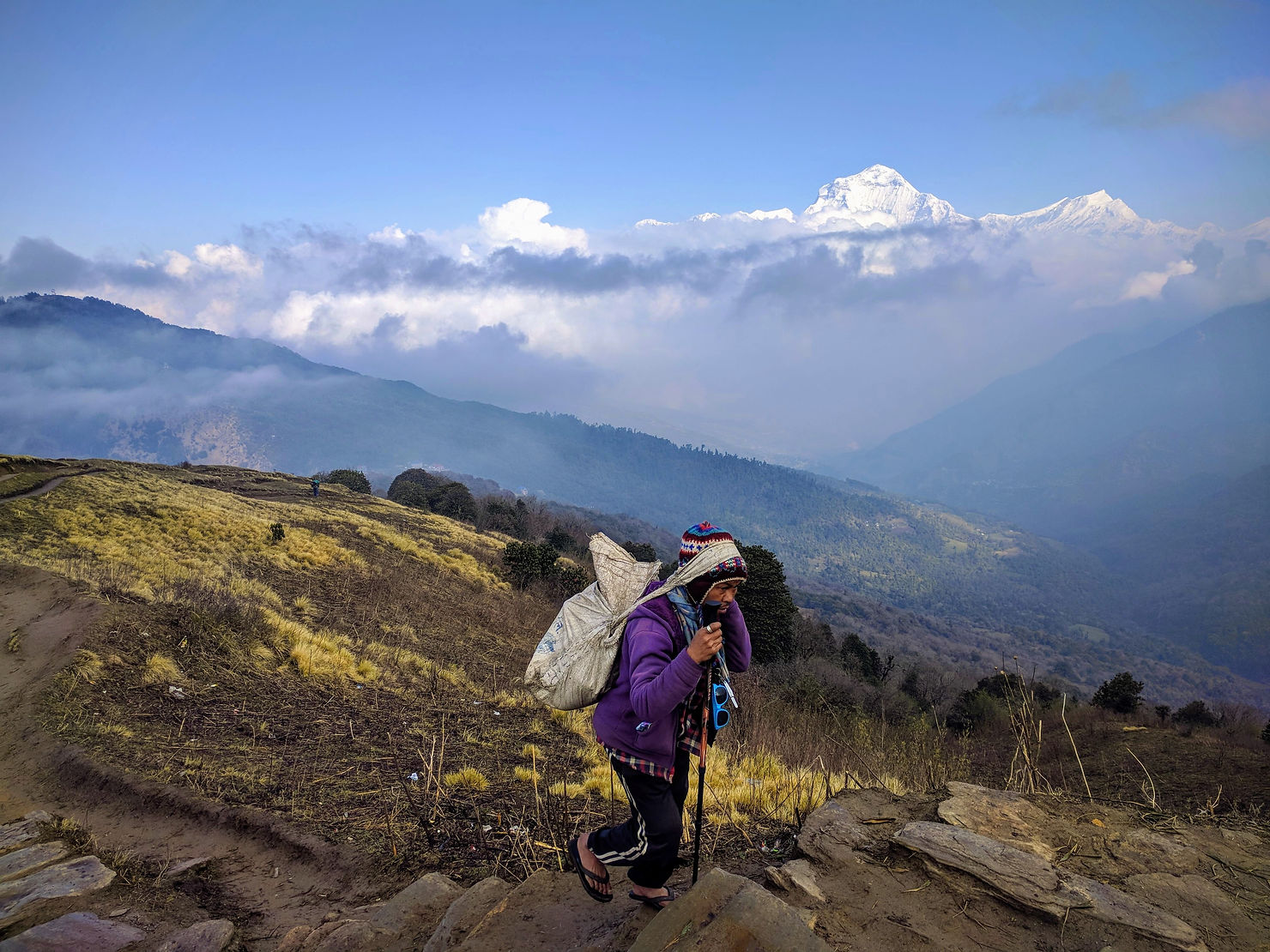 a porter carrying a load and walking on the trail in mountain area of Nepal