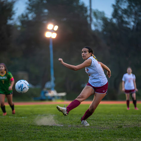 Ladies football sessions on a grass field with a player crossing the ball over to her teammate