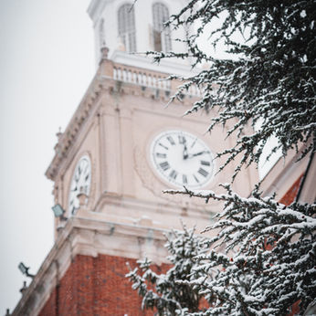 Howard University's clock tower next to a snow-topped tree
