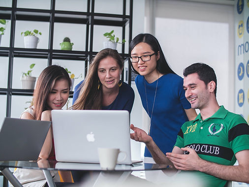 A diverse group of recent grads look at a laptop and plan business, reflecting the talent pipeline of Alberta SouthWest.