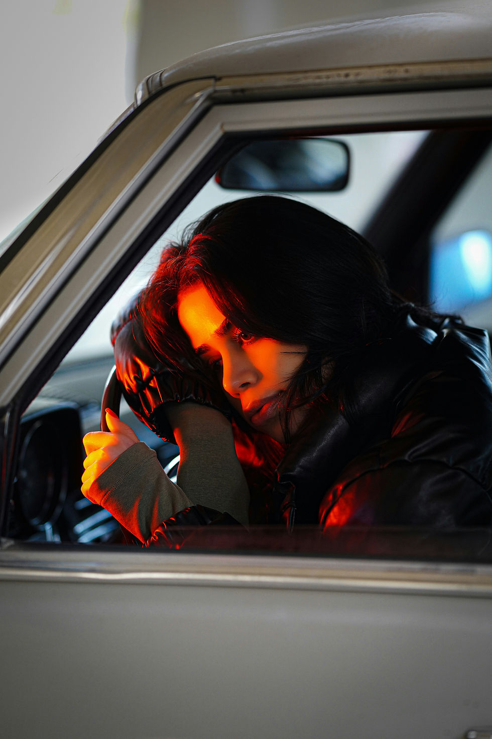 A woman in her car laying on the steering wheel