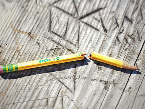 Broken yellow pencil with green eraser on weathered wood, showing SOFT 2 HB text.