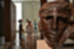 sculpture of a face in a gallery with blurred people in the background