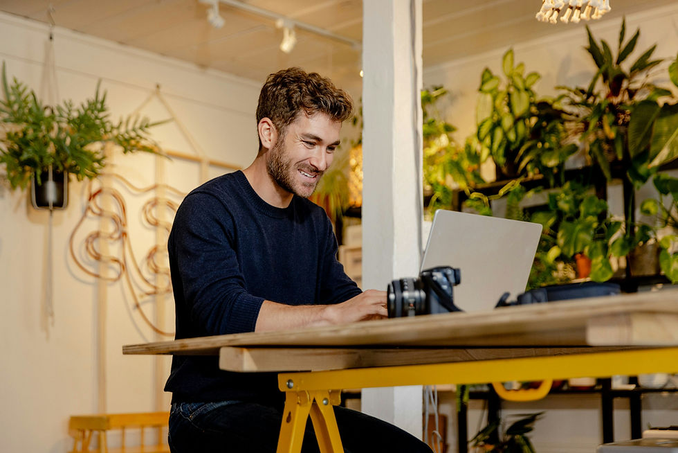 Zur Website-Analyse: Inhaber arbeitet lächelnd am Laptop in seinem Atelier