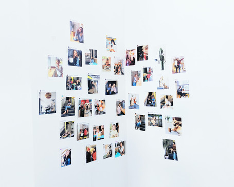Array of photos hanging on a white wall; THE PORTABLE VISION BOARD, corner setting.