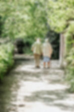 An older couple walking outdoors amongst trees