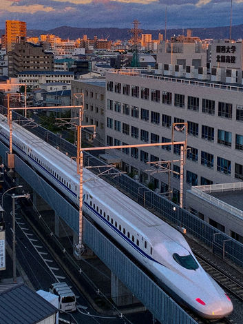 Shinkansen bullet train traveling through urban skyline in Japan.