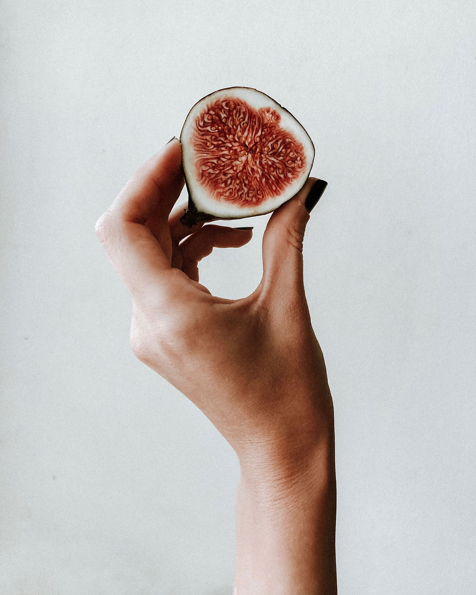 hand holding a fig that is cut in half with a white background