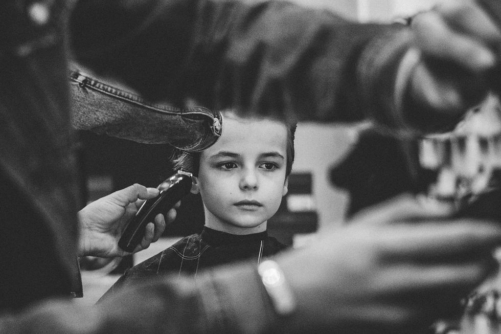 A black and white picture of a young boy getting his hair cut.