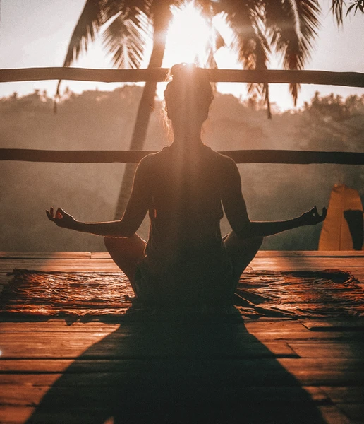 a woman sits in a lotus position on a wooden deck
