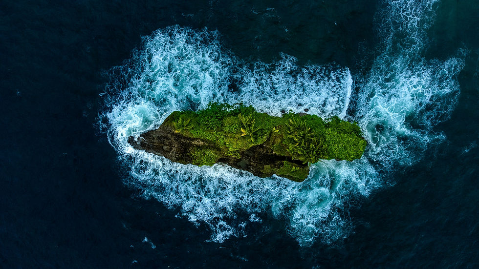 Aerial view of a small, lush green island surrounded by crashing white waves in deep blue ocean. Vibrant, isolated, and serene setting.