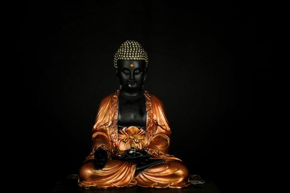 A bronze Buddha statue with a serene expression, adorned with intricate patterns, sits against a dark background. Soft lighting highlights details.