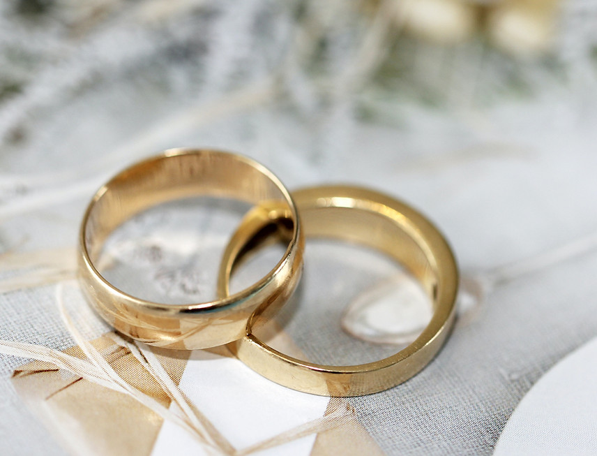 Deux alliances en or sur un fond élégant pour une page de planification musicale de mariage.