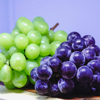 Green and purple grapes on wooden board
