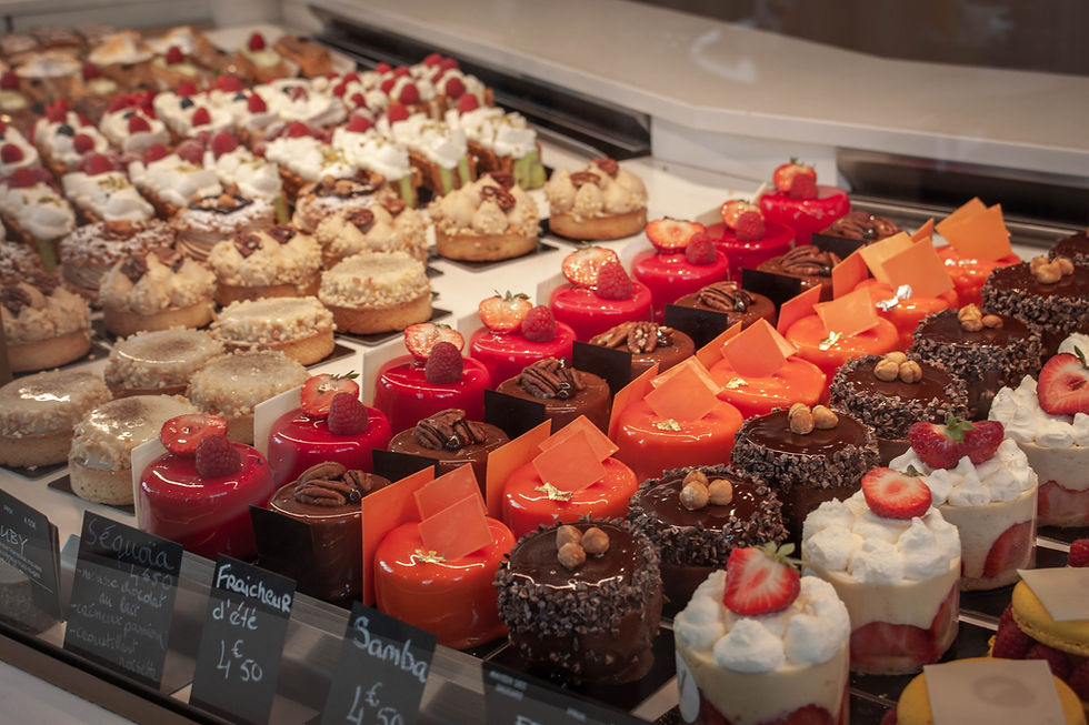 Assorted pastries on display, featuring vibrant colors and toppings like strawberries, raspberries, and nuts. Price tags visible. Sweet temptation.