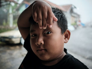 A young boy lifting his hand above his face to reveal one eye, highlighting childhood eye health and the importance of early vision care. | South Bay Retina, San Jose, Gilroy
