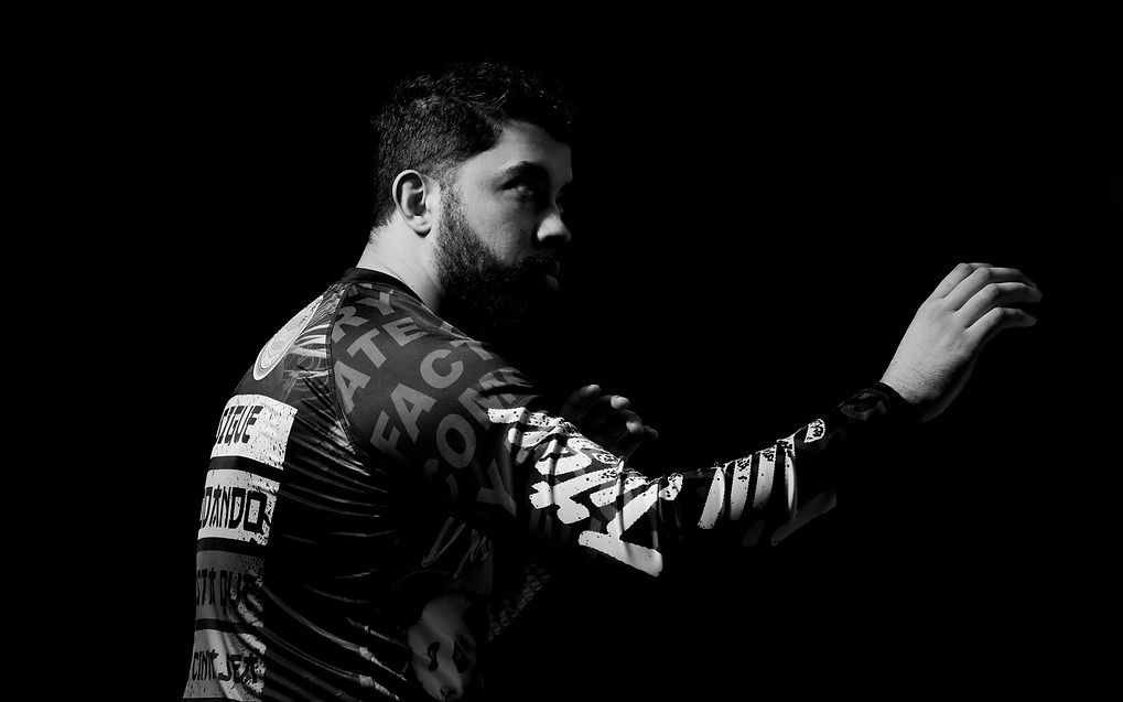 Intense moment of BJJ submission attempt in black gi with focused lighting.