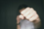 Closeup of a fist with the blurred image of a person throwing a punch behind it