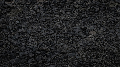 Close-up texture of dark, coarse volcanic soil and pebbles.
