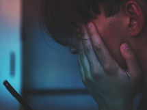 Tired and upset teenager looking at his smartphone