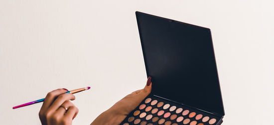 Hands holding an eyeshadow palette and brush
