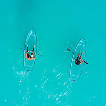 Two people on paddle boards on crystal-clear turqouise waters
