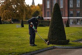 man strimming he edge of a lawn at a luxury manor house