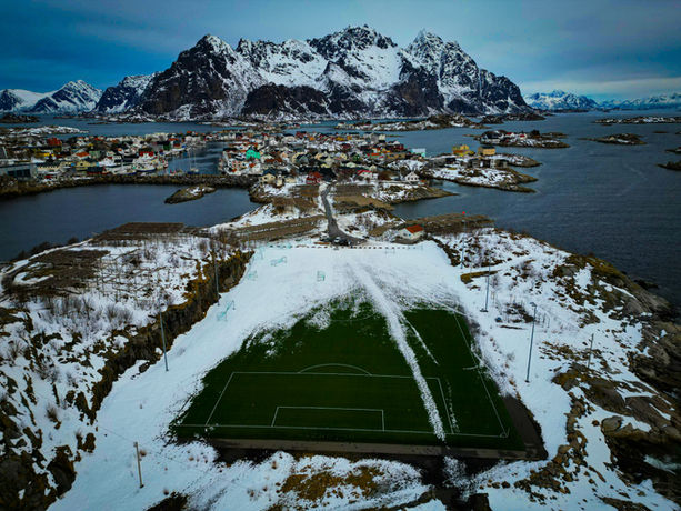 Veduta aerea di Henningsvær alle Lofoten con campo da calcio e montagne innevate