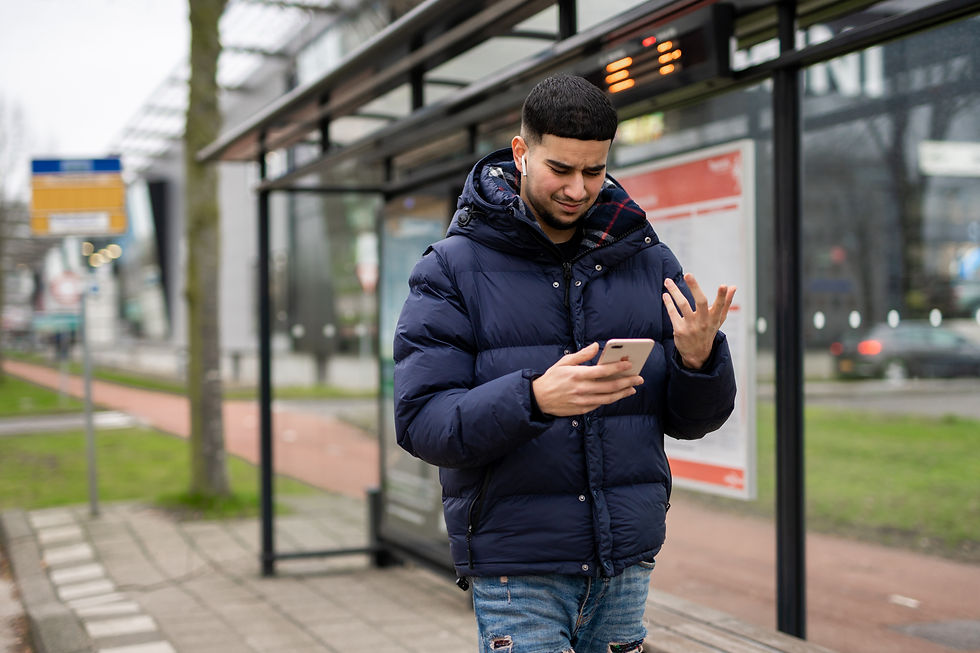 a nervous-looking man rehearsing answers on a bus stand, phone in hand