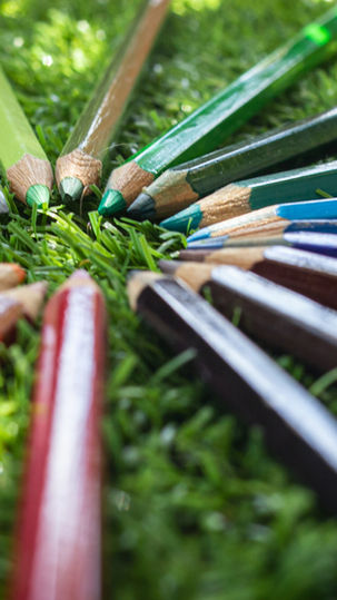 A circle of rainbow colored pencils in grass