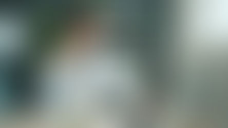 Holistic doctor using a laptop and smartphone in a calm, plant-filled workspace focused on patient care and research.