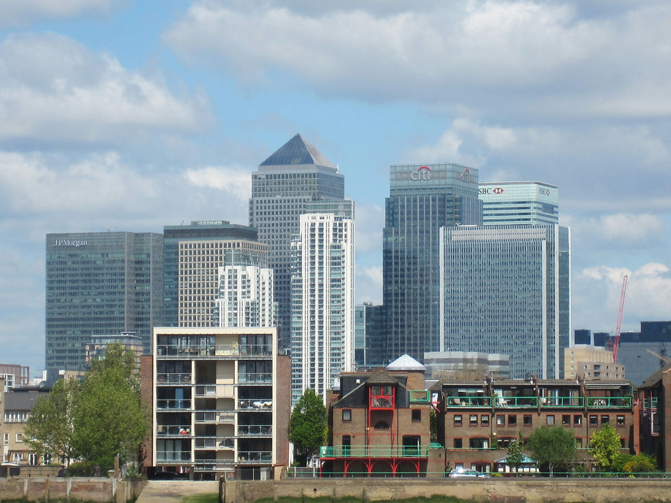 Canary Wharf skyline with modern skyscrapers and older brick buildings in the foreground. Clear blue sky with clouds. Text: Citi, HSBC, JPMorgan.