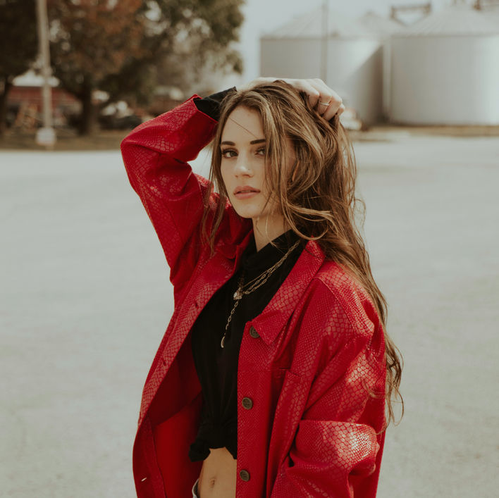 Woman with long hair in a red jacket, hand in hair