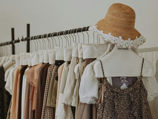 A neatly organized clothing rack displaying a curated selection of apparel pieces that reflect the evolving direction of SS27 Changes across the fashion industry, showing a mix of light layered garments, patterned tops, and casual outerwear hanging in sequence on wooden and metal hangers against a plain neutral background, representing the kind of seasonal assortment that fashion distributors and retail buyers need to plan for as SS27 Changes influence collection structure, color direction, and order volume, with the rack composition suggesting a showroom or distributor warehouse setting where SS27 collections are reviewed, sorted, and prepared for retail buyer presentations ahead of the Spring Summer 2027 order booking window, making this image a visual representation of the operational side of SS27 Changes that distributors must manage efficiently through structured catalog and order tracking systems.