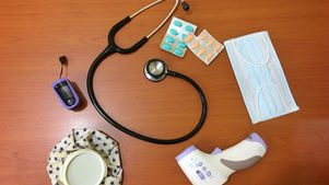 Northeast Radio SD logo on a wood table with a stethoscope, pills, masks, thermometer, pulse oximeter, and ice pack