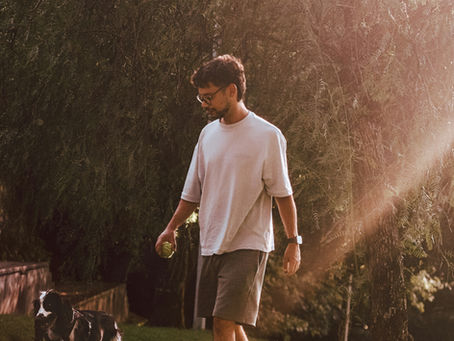 Man walking a dog outdoors in a natural setting, representing the positive impact of nature, movement, routine, and outdoor activity on mental wellbeing.
