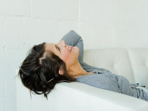 Woman with arthritis relaxing on white couch.