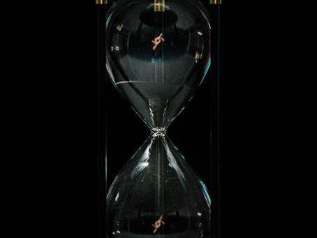 Hourglass with sand running through it against a dark background