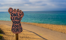 Beach with sign of foot with text about leaving footprints