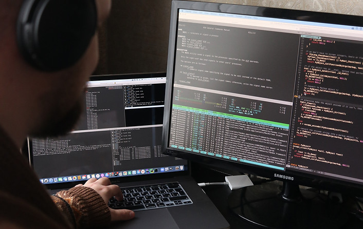 Man reading code off a computer screen. Image by Mikhail Fesenko