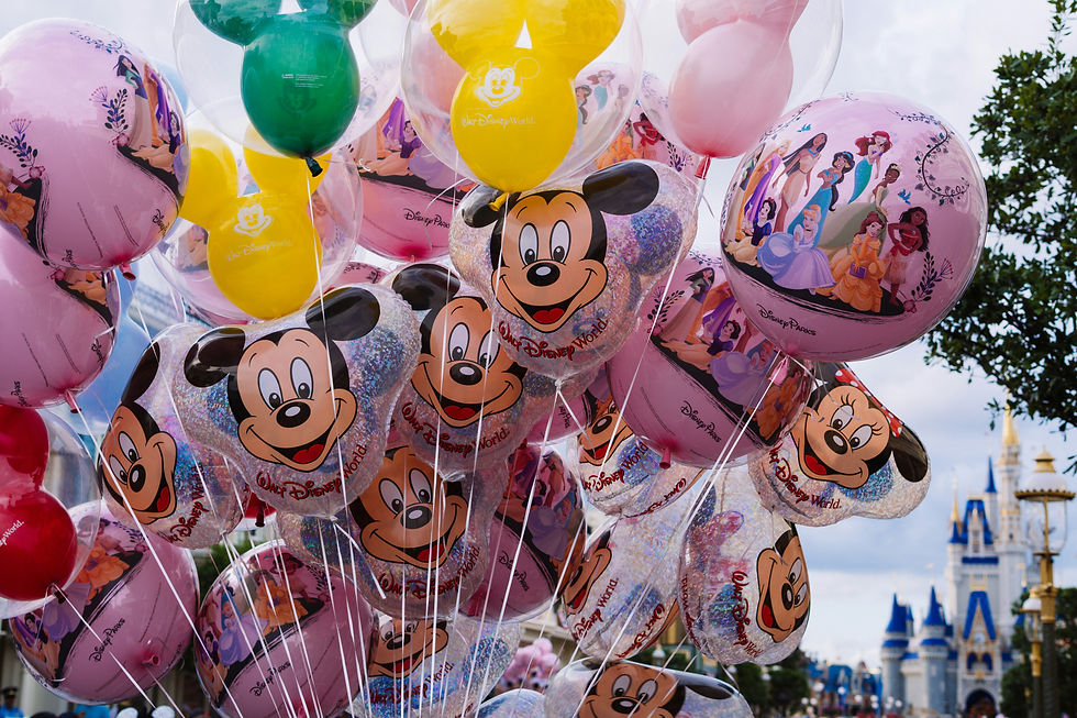 Colorful Disney balloons featuring Mickey and princesses float before Cinderella Castle at Walt Disney World.